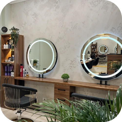Moderno opremljen ženski frizerski salon sa elegantnim okruglim ogledalima, stilskim stolicama i funkcionalnim radnim prostorom.